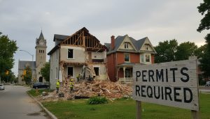 House demolition site in Georgetown, Ontario with permit sign and town hall in background