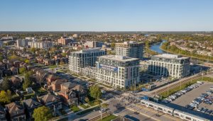 Aerial view of Georgetown, Ontario with new mid-rise condo construction beside established neighbourhoods and GO station commuters.