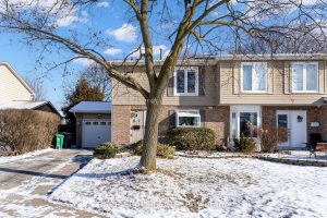 Suburban house in winter with snow-covered lawn.