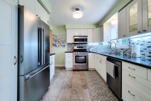 Modern kitchen with stainless steel appliances and tile backsplash.