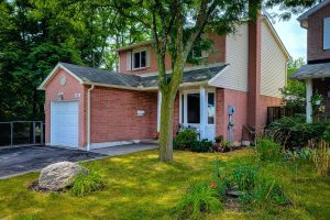 Red brick house with garden and tree.