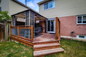 Backyard wooden deck with gazebo and grill.