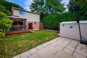 Backyard with deck, basketball hoop, and shed.