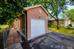 Brick garage with white door and tree nearby.