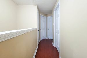 Narrow hallway with white doors and wooden floor