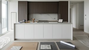 Modern condo kitchen under renovation with cabinets, flooring samples, blueprints and tools