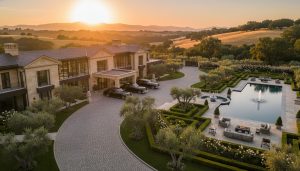 Luxury estate home at golden hour with manicured gardens and grand entrance, photographed from a drone perspective