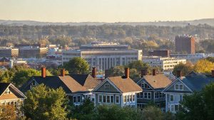 Cityscape with historic houses, modern buildings, and trees.