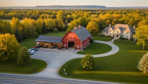 Luxury rural property near Milton Ontario with a red barn and attached heated workshop at golden hour, organized bays visible and escarpment in background.