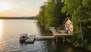 Summer lakefront cottage for sale with dock and 'For Sale' sign near Milton, Ontario