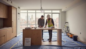 Homeowner and contractor reviewing renovation plans inside a Georgetown condo with documents and permit forms on the table.