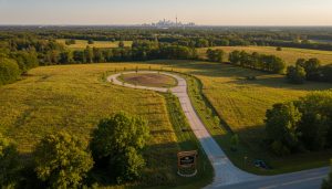 Aerial view of vacant luxury lot near Georgetown Ontario with 'For Sale' sign, driveway, and mature trees