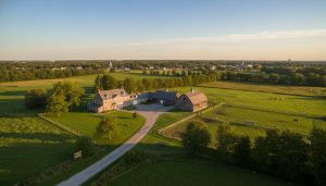 Aerial view of luxury farmhouse, barn, and fenced pastures near Georgetown Ontario at golden hour