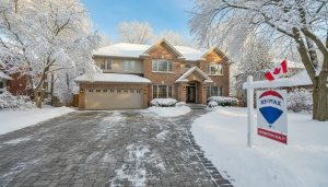 Georgetown Ontario family home in winter with cleared driveway, warm lights, and real estate sign