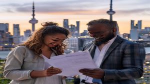 Smiling colleagues reviewing documents on rooftop at sunset