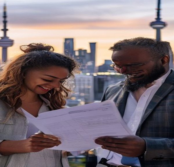 Smiling colleagues reviewing documents on rooftop at sunset